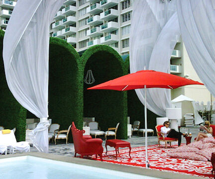 A serene pool with a vibrant red umbrella.